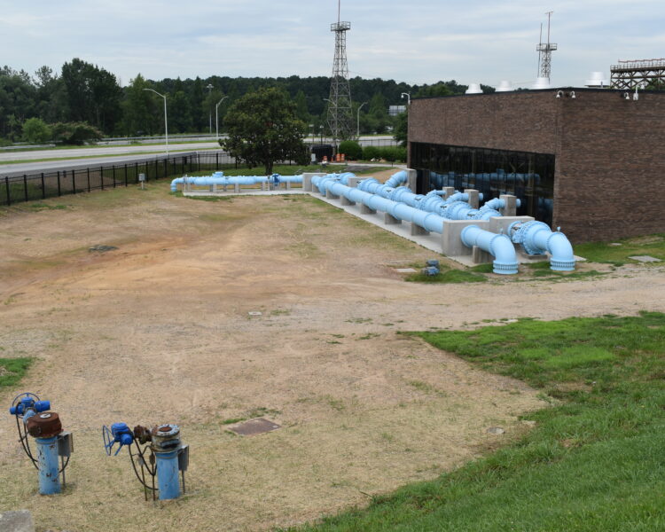 Las tuberías azules se conectan a una instalación de agua de ladrillo situada en un terreno cubierto de césped.