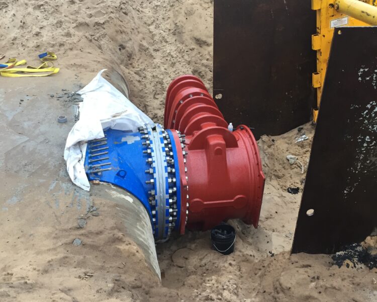 Red and blue pipe in sand at construction site.