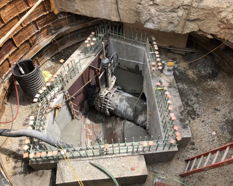 Large pipe in concrete structure at excavation site with equipment.