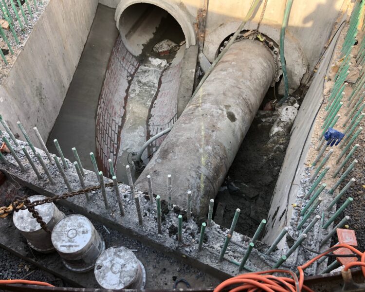 Concrete culvert site with large pipe, rebar, and cables.