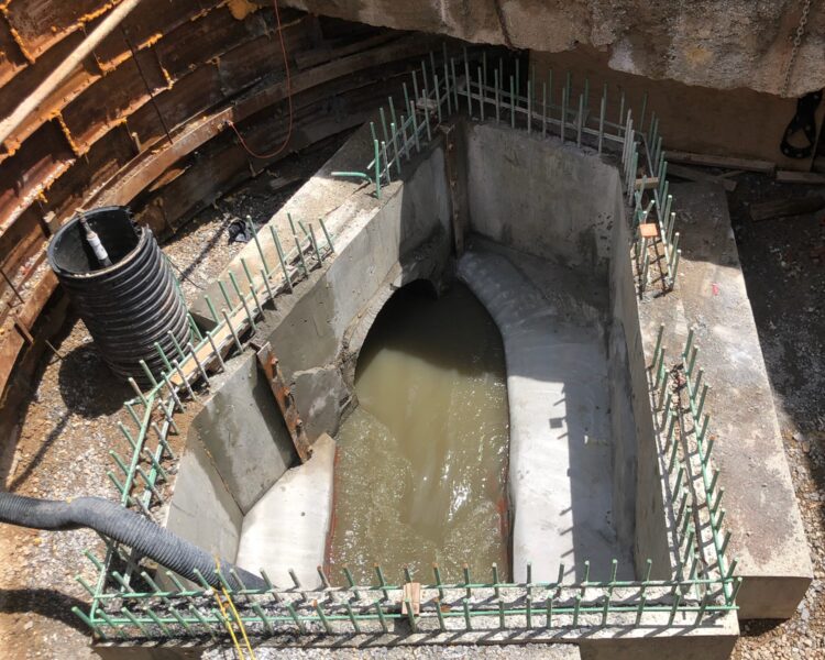 Concrete ring with rebar, water, pipes, and debris nearby.