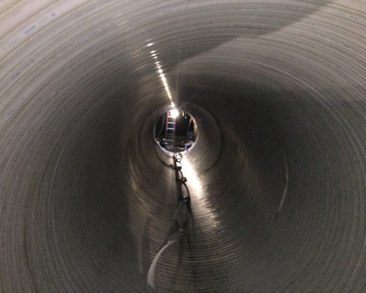 Inside large pipe, light and ladder visible at opening.