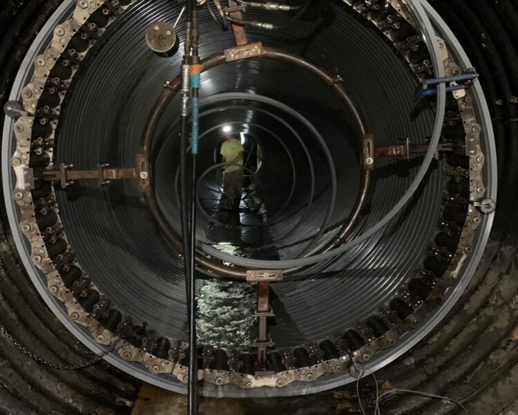 Un trabajador dentro de un túnel cilíndrico con equipos en las paredes.
