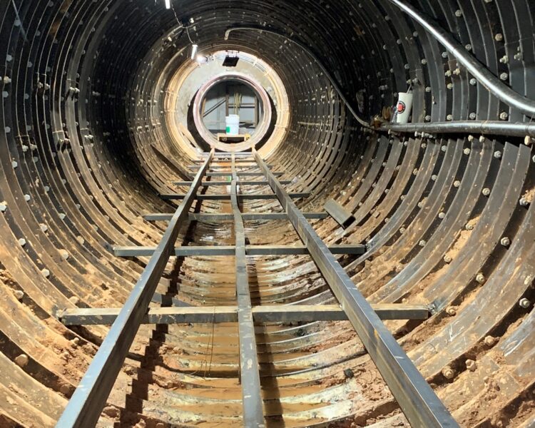 Túnel cilíndrico en construcción con vías y cables.