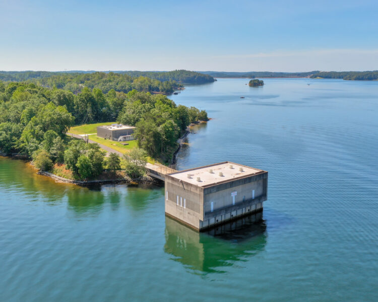 Concrete utility building in water near trees and sky.