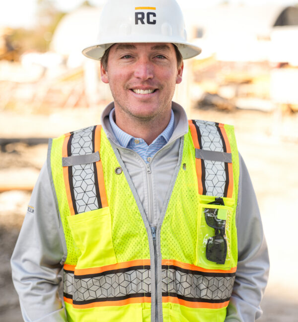 Smiling construction worker in RC hard hat and safety vest.