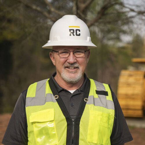 Smiling man in hard hat and safety vest at construction site.